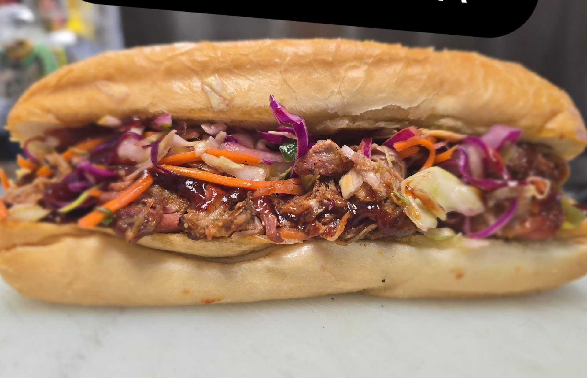 Grilled sandwich with pulled pork and colorful slaw in a bun.