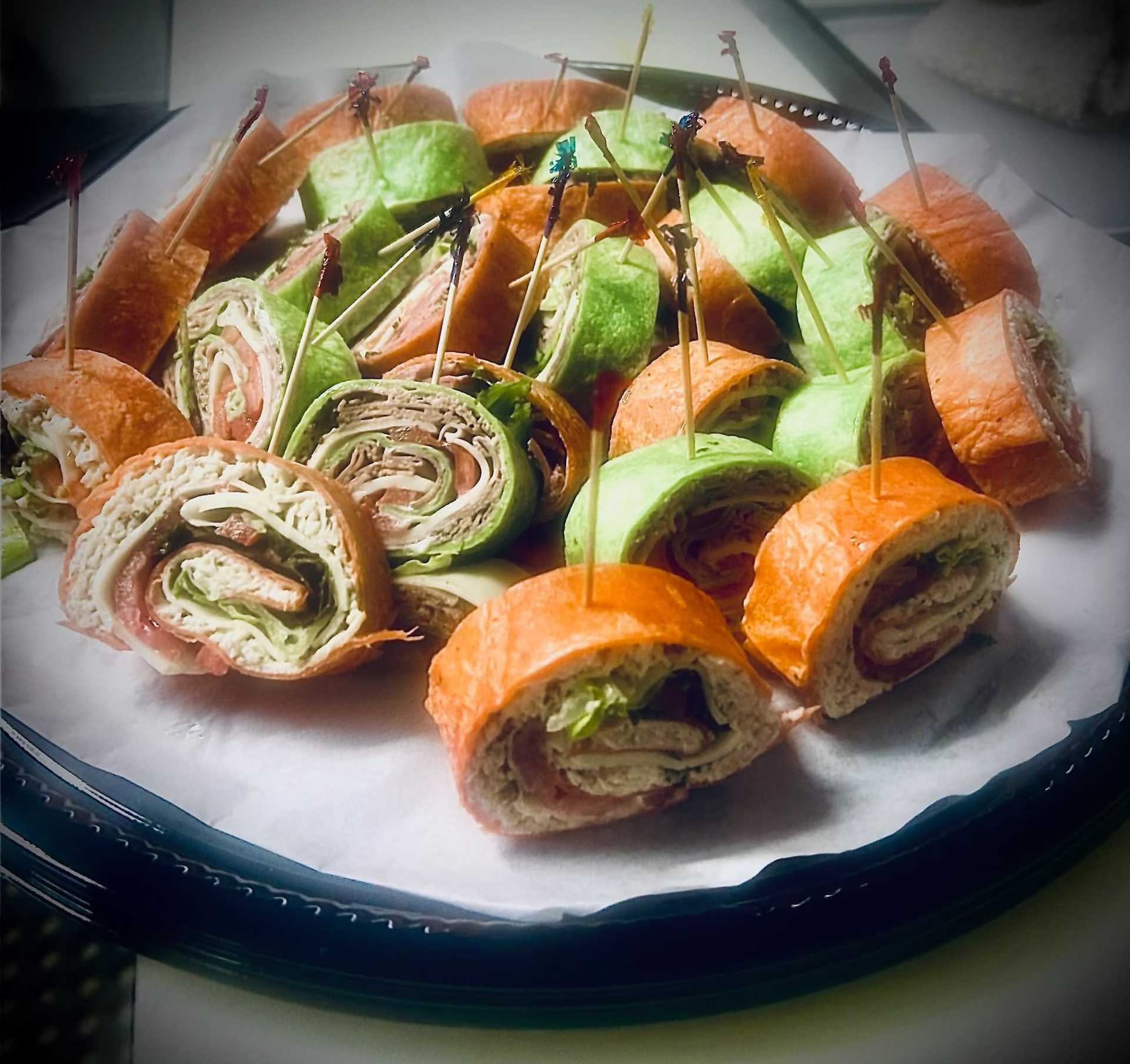 Platter of assorted wrap sandwiches with colorful toothpicks on a tray.